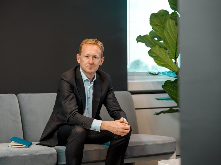 Joe O’Malley, Managing Partner at Hayes Solicitors LLP seated on a gray couch